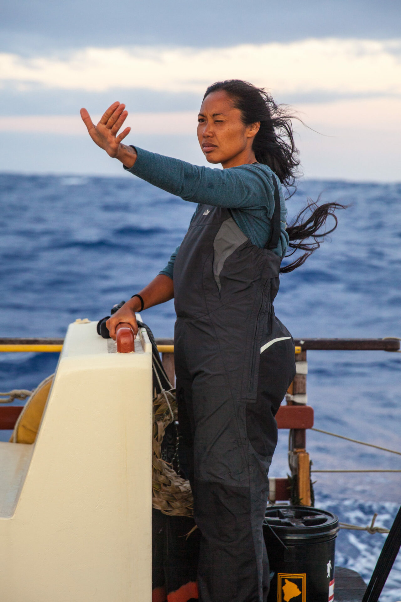 woman at boat helm pointing with her right hand
