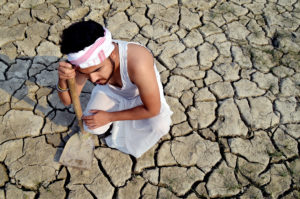 farmer sitting on parched agricultural land