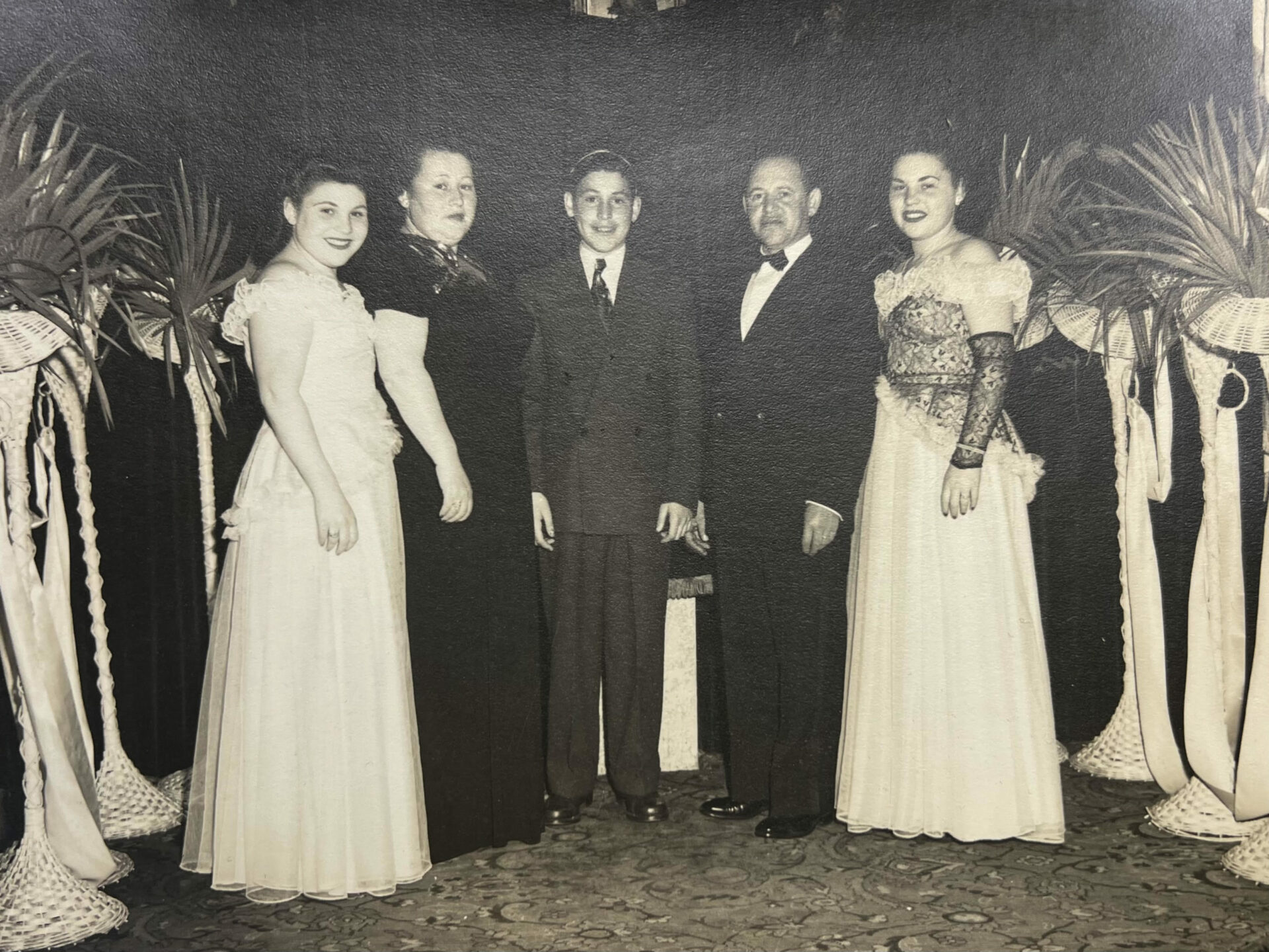 A photograph from 1945 of a man at his bar mitzvah with his parents and two sisters standing next to him.