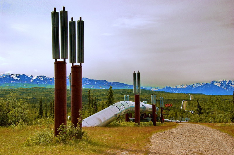 view of 800-mile Trans-Alaska Pipeline from a dirt road in the foreground to mountains in the far distance
